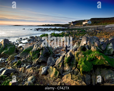 Dawn breaks over the rugged coast at Port Eynon on the Gower Peninsula. Stock Photo