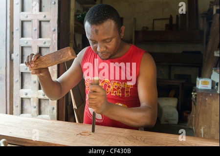 Carpenter carving an ornate frame for a bed Stone Town Zanzibar Tanzania Stock Photo