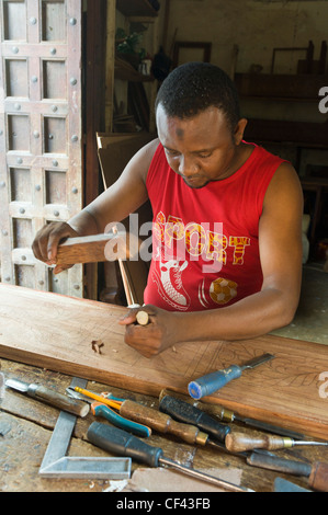 Carpenter carving an ornate frame for a bed Stone Town Zanzibar Tanzania Stock Photo