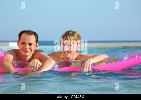 young man and nice women lying on an inflatable mattress in pool Stock Photo