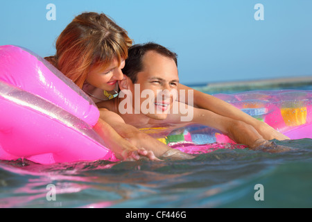young man and nice women lying on an inflatable mattress in pool Stock Photo