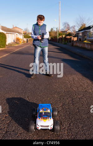 A 12 year old boy playing with his radio controlled car in the street in England , Britain , Uk Stock Photo