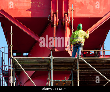 Industrial worker standing on scaffolding around a steel structure, looking up Stock Photo