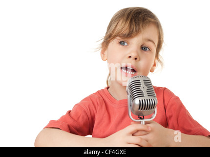 pretty little girl in red T-shirt sing in old style microphone isolated on white background, looking aside Stock Photo