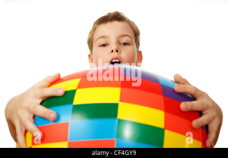 Boy holds before itself big inflatable multi-coloured ball, having captured his hands. Isolated on white background. Stock Photo