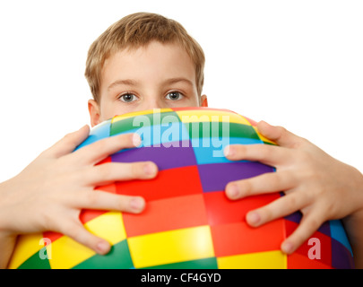 Boy holds in front of himself big, multi-coloured, inflatable ball, looking out from behind it. Looks in camera. Stock Photo