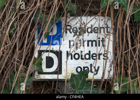 resident permit holders only parking sign partly obscured by vegetation Stock Photo