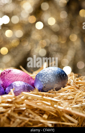 Chocolate Easter eggs in a natural straw nest in front of a beautiful golden background Stock Photo