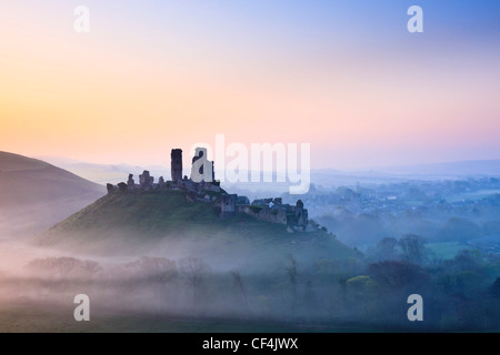 Corfe Castle, dating back to the 11th century, shrouded in mist at sunrise. Stock Photo