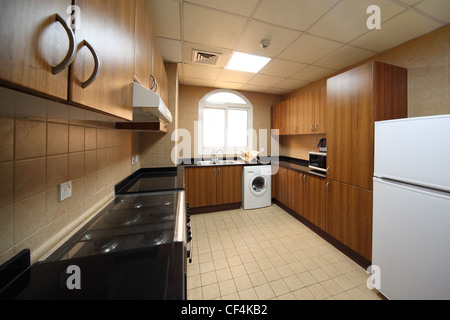 kitchen with brown cupboards, washingmachine, cooker and fridge Stock Photo
