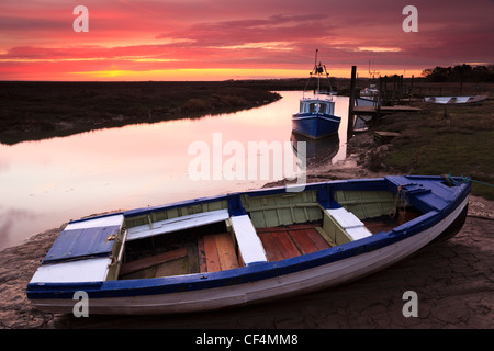 Small boats moored in Thornham Harbour at sunrise. Stock Photo