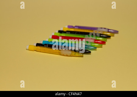 Nine coloured mechanical pencils on a pale lemon yellow background Stock Photo