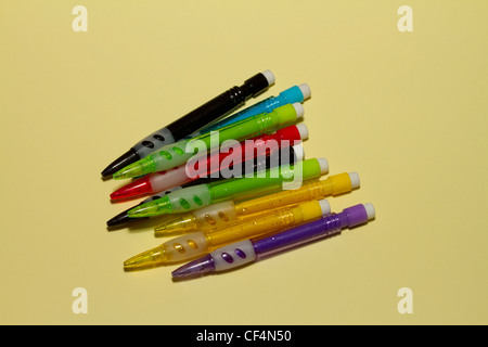 Nine coloured mechanical pencils on a pale lemon yellow background Stock Photo
