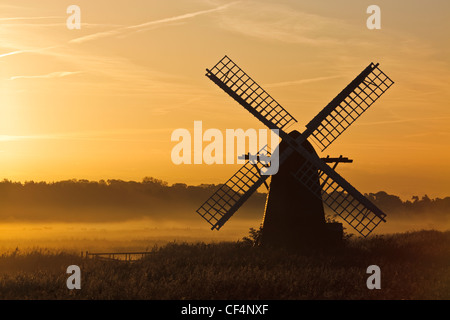 Herringfleet mill or Walker's Mill, a 19th century fully restored octagonal drainage mill silhouetted against the dawn sky on a Stock Photo