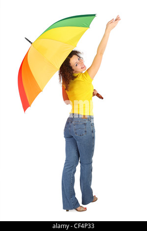 young beauty woman in yellow shirt with multicolored umbrella standing with reached out a hand isolated on white, view from back Stock Photo