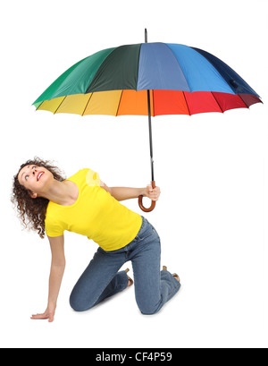 young attractive woman in yellow shirt with multicolored umbrella sitting isolated on white and looking up Stock Photo
