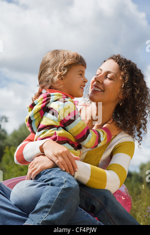 mother and the daughter play in the open air, sitting on an inflatable armchair. looking in eyes