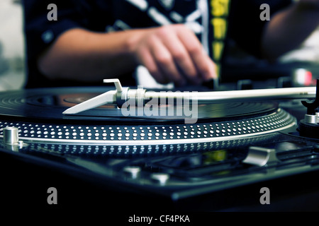Focus on the professional turntable with a DJ adjusting the volume on controller Stock Photo