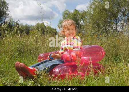 young girl in summer day rest in the open air sitting on an inflatable armchair