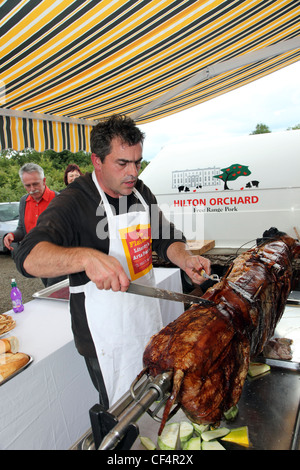 Film director Kevin Allen carving a Hilton Orchard Pig Roast. Allen runs Flatlake, a literary/ music festival at Hilton Park, an Stock Photo