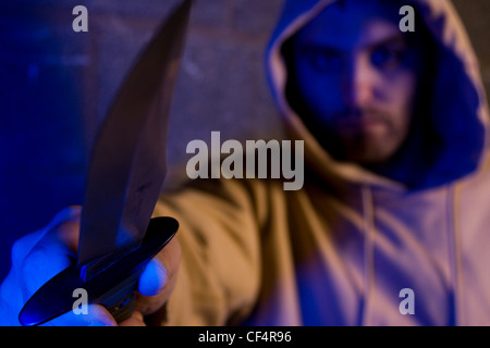 Hooded gang member holding out a knife. Stock Photo