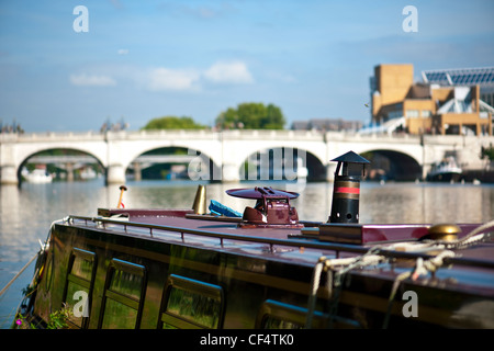 A canal barge moored on the River Thames with Kingston Bridge in the background. Stock Photo