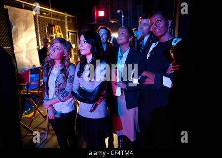 First Lady Michelle Obama watches a performance backstage with iCarly cast members Jennette McCurdy, left, and Miranda Cosgrove and members of her staff prior to an iCarly screening at Hayfield Secondary School January 13, 2012 in Alexandria, VA. Stock Photo