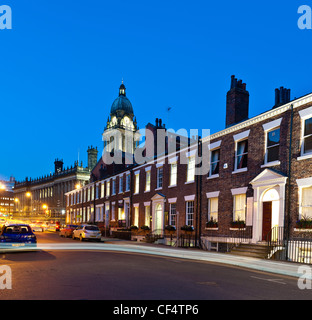 Leeds Town Hall and Georgian terrace houses at night with light trail of passing car. Stock Photo