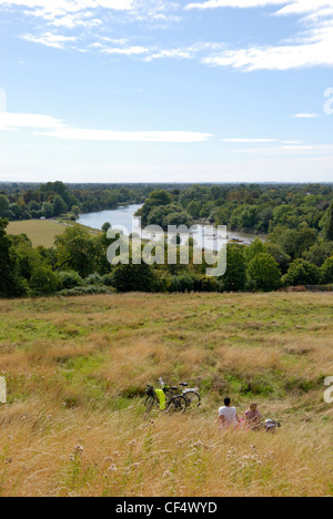 A couple taking a break from their cycle ride enjoying the view of the River Thames from Richmond Hill. Stock Photo