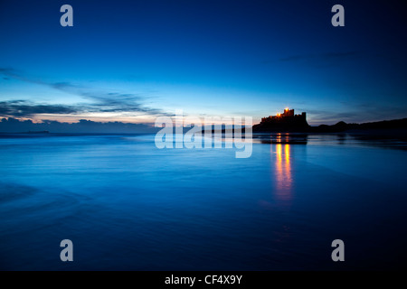 Lights from Bamburgh Castle reflecting in the low tide just before dawn. Stock Photo