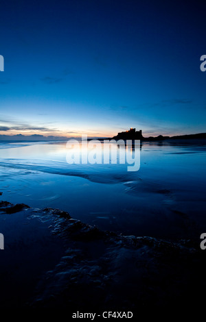 Lights from Bamburgh Castle reflecting in the low tide just before dawn. Stock Photo