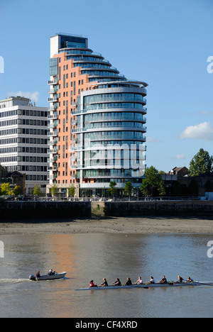 A womens eight training on the River Thames by Putney Wharf Tower (also known as Bridge House). Stock Photo