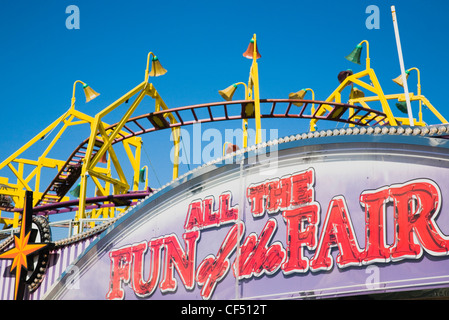 Skegness Facade of amusement arcade with rollercoaster behind in clear blue sky British English Britain England East Coast Stock Photo