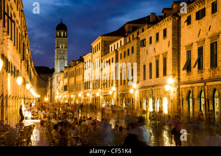 People eating at restaurants main street with Franciscan Monastery tower at dusk, Old City of Dubrovnik, Dubrovnik, Croatia Stock Photo