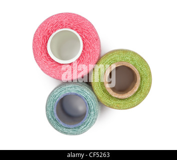 Three coils with multi-coloured sewing threads isolated on white background, top view Stock Photo