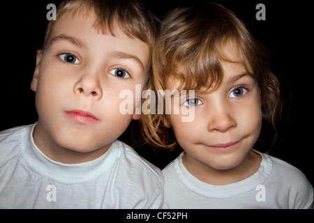 boy and little girl in white T-shirts isolated on black background Stock Photo