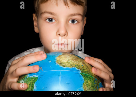 boy keeps in hands over globe of world isolated on black background Stock Photo