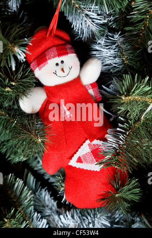 smiling toy snowman in red clothes hanging on Christmas fur-tree Stock Photo