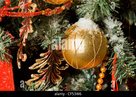 Christmas toy in form of sphere hanging on artificial fur-tree, sphere in snow Stock Photo