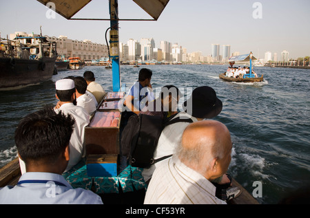 UAE, Gulf State, Dubai, Abra water taxis with passengers passing on the Creek with Twin Towers and skyline behind. Stock Photo