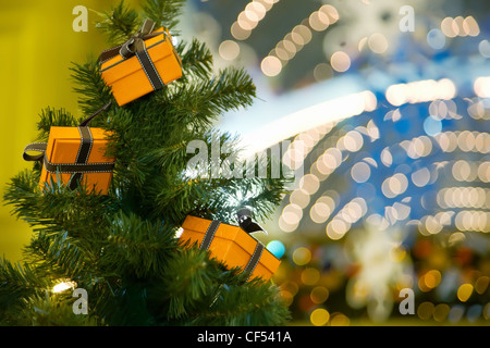 Three celebratory gifts in yellow boxes hanging on Christmas fur-tree Stock Photo