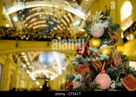 Fur-tree densely covered by Christmas ornaments in shopping centre Stock Photo