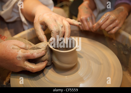 Hands of master creating pot on potter's wheel. Traditional craft. Focus on the hands. Stock Photo