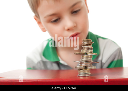 boy in striped T-shirt  looking at curve pile from coins coins  isolated on white background Stock Photo