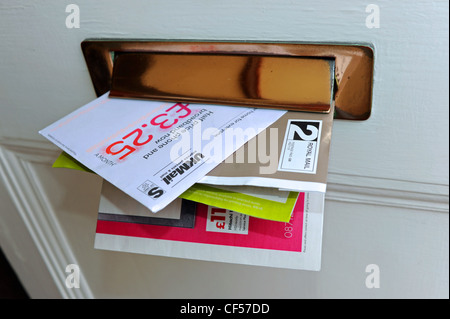 Junk mail in a private home letter box being posted through front door UK Stock Photo
