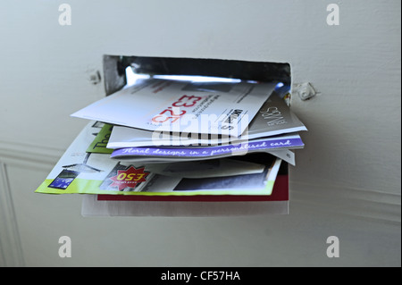 Junk mail in a private home letter box being posted through front door UK Stock Photo