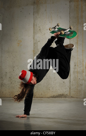 Skateboarder performing tricks with grungy wall as background Stock Photo