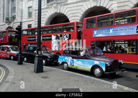 Three traditional London taxi cabs and three red London buses with elegant Victorian buildings in the background. Stock Photo
