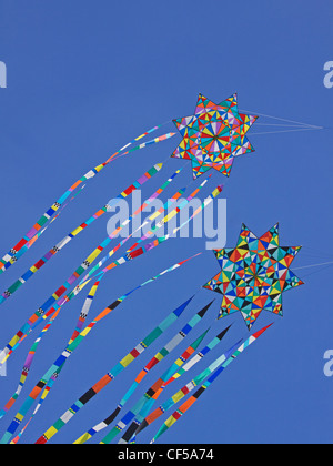 Colorful kites riding on the breeze against a clear blue sky