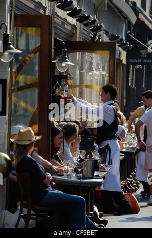 A waiter and customers outside a bar restaurant in Old Compton Street. Stock Photo